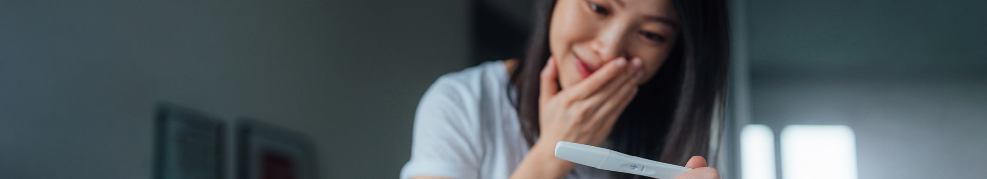 Person looking at pregnancy test and smiling.