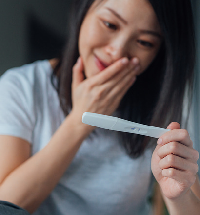 Person looking at pregnancy test and smiling.