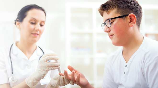 Adolescent boy with diabetes getting a finger stick to check blood sugars