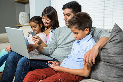 Family looking at screens while sitting on couch