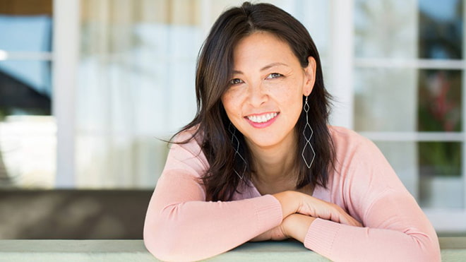 smiling-middle-aged-woman-with-her-arms-crossed-leaning-on-a-railing