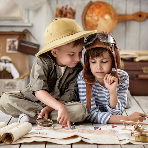 Two young boys exploring a map indoors