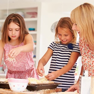 Two young girls and mother preparing a meal