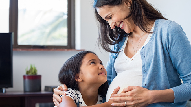 Girl and mom touching pregnant belly