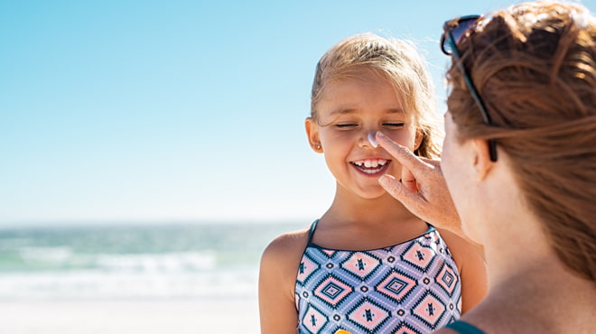 Mom putting sunscreen on girl's nose