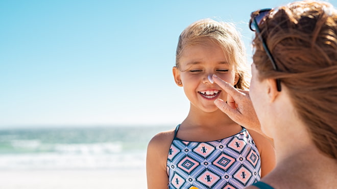 Mom putting sunscreen on girl's nose