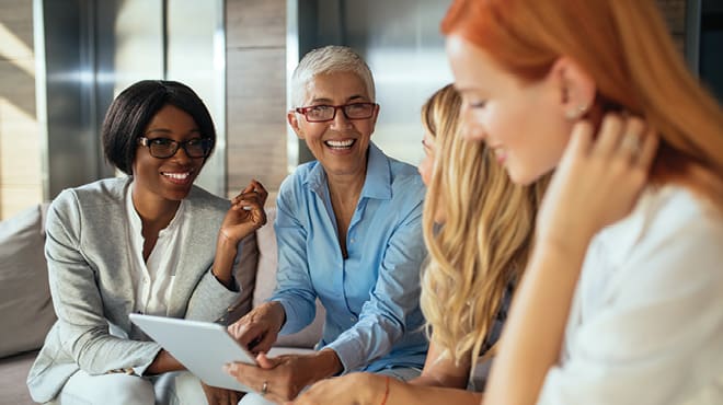 Women talking around a laptop