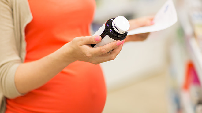 Pregnant woman looking at supplements