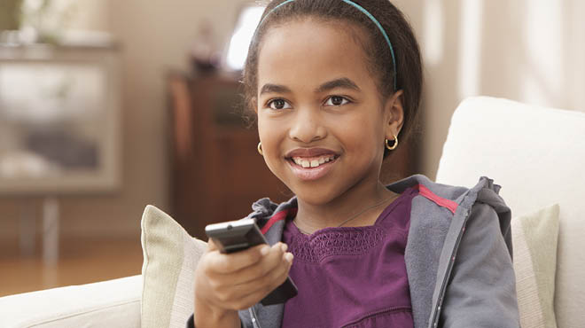 Child sitting with TV remote in hand