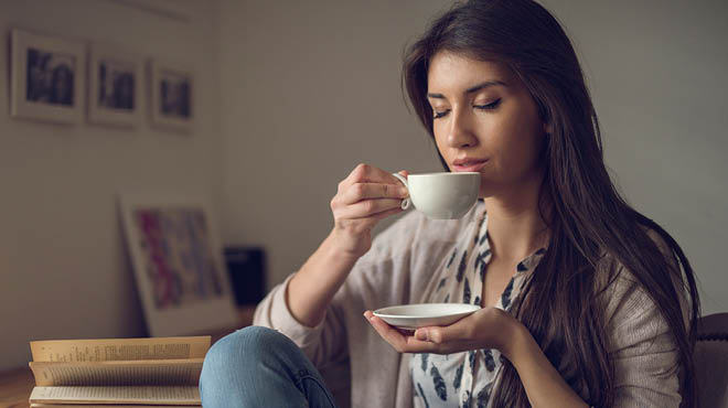 Holding cup and saucer eyes closed