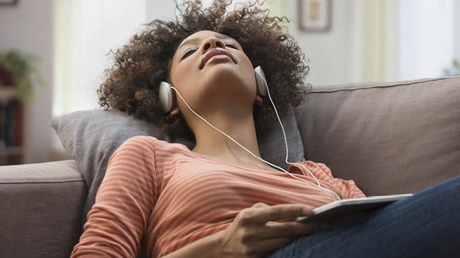 Listening with headphones lying on sofa