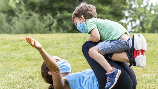 Masked mom and child playing outdoors