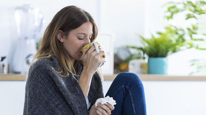 Person feeling sick, drinking beverage, holding tissue