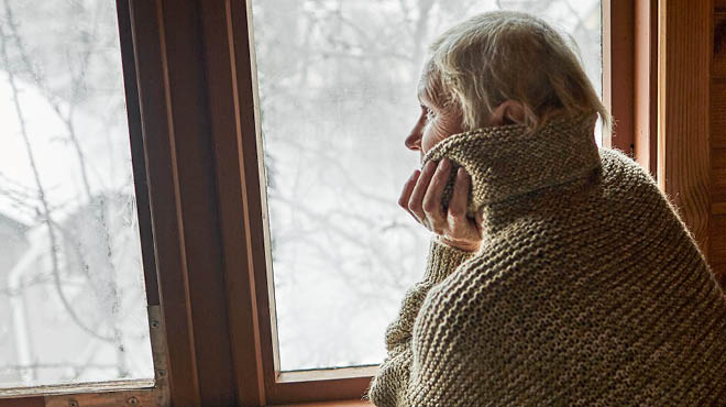Senior person looking out window in winter