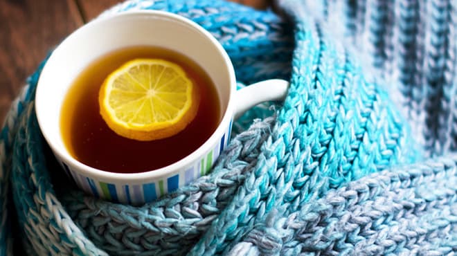 Tea with lemon in cup wrapped in knitted yarn
