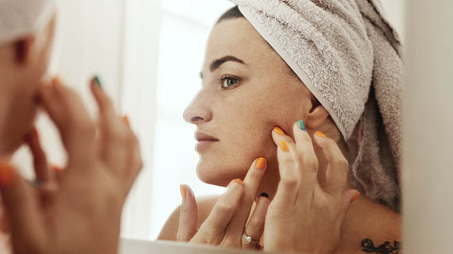 Looking in mirror, towel covering head, touching face