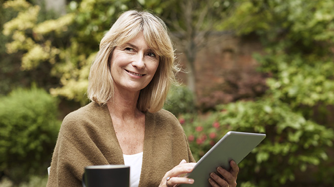 Person using tablet outdoors and smiling