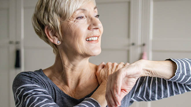 Person lifting arm with opposite hand on shoulder
