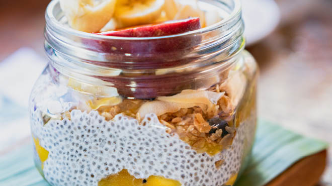 Chia seeds in jar mixed with yogurt, fruit and granola