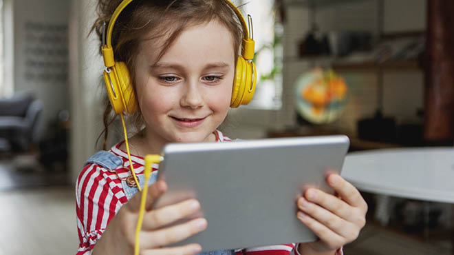 Child wearing earphones using tablet
