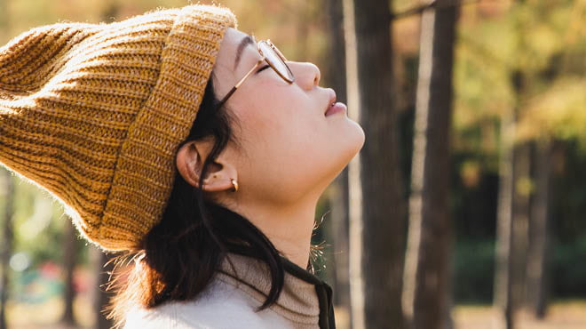 Face upward to the sky with eyes closed, wearing a knit hat