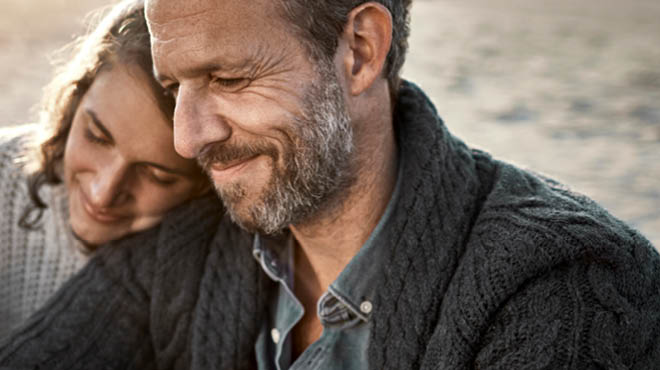 Person with grey beard and grey knit sweater with a partner