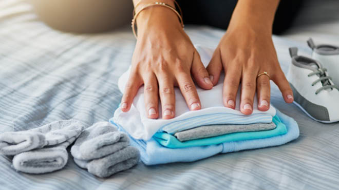 Hands on folded baby clothes