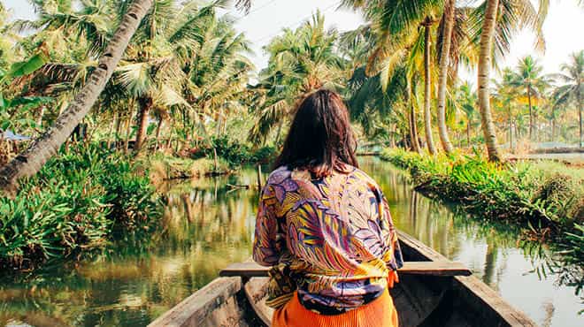 Person sitting in wooden boat on the water in a tropical location