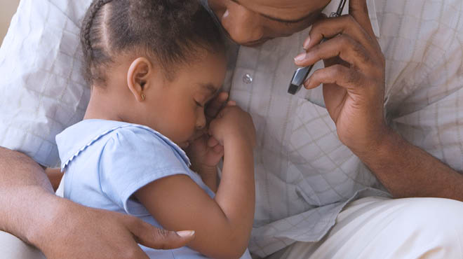 Parent holding sick child while on the phone