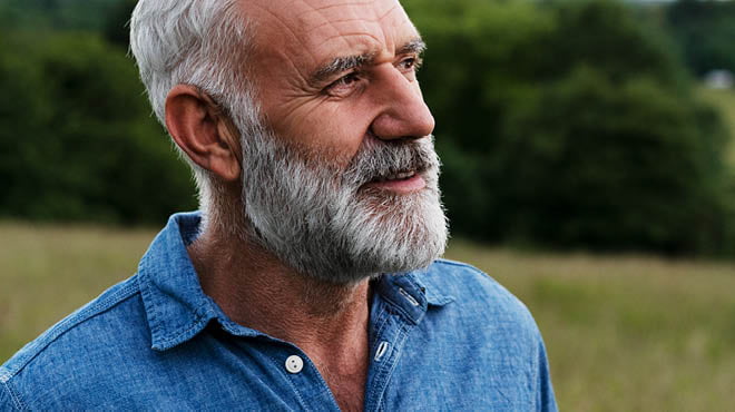 Person with grey beard, wearing a denim shirt