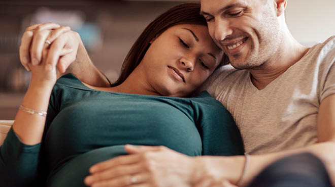 Pregnant woman with partner's hand on belly