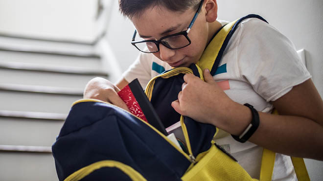 Student putting notebook in backpack