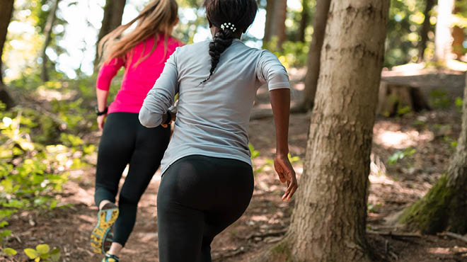 Two people running on wooded trail