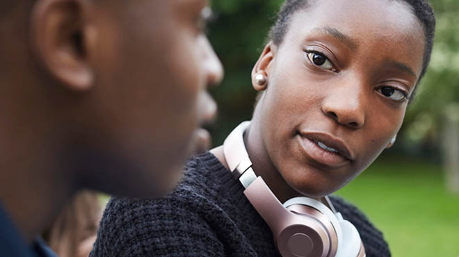 Two people talking with one wearing headphones around the neck