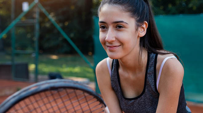 Young person on tennis court holding tennis racket