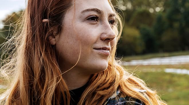Close-up of young person with long reddish hair looking to their left