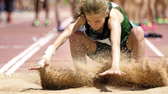 Athlete landing jump in sand