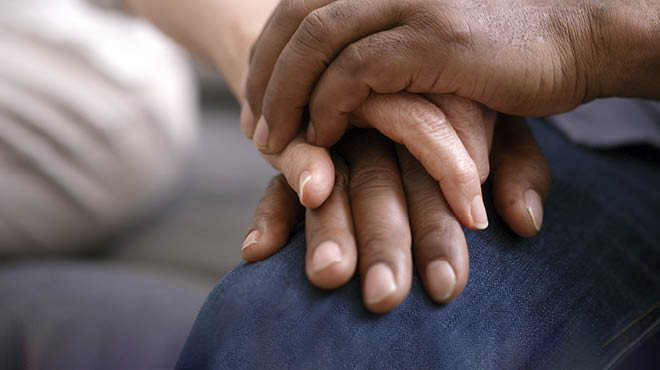 Female hands touching body of sporty young man on dark background