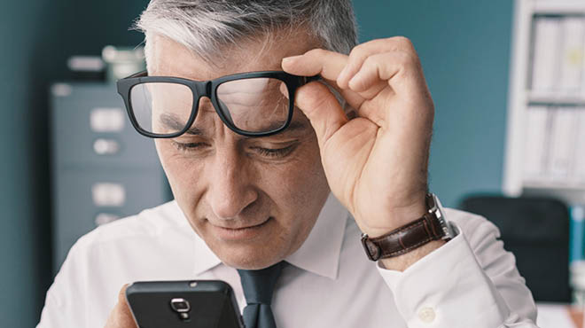 Lifting eyeglasses looking at phone