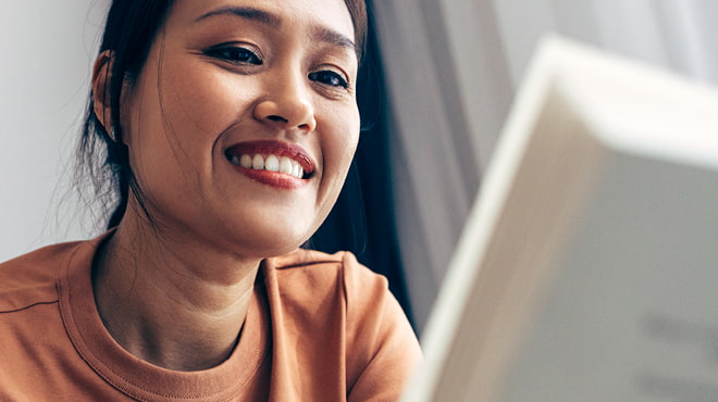 Person smiling while looking at computer screen