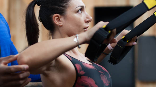 Trainer teaching student to use TRX