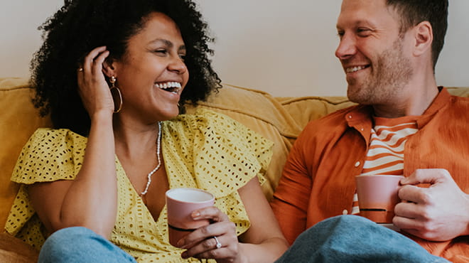 Two people on sofa holding cups