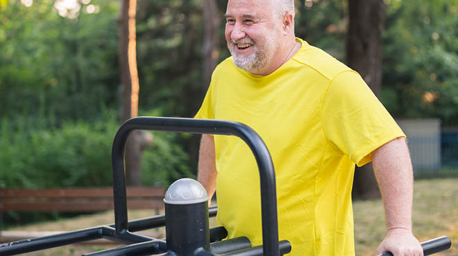 Person with yellow shirt using outdoor exercise equipment