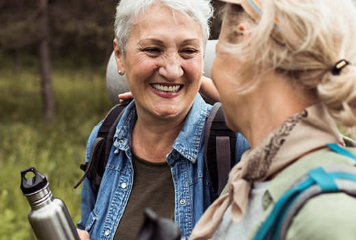 Two people outdoors, smiling, wearing backpacks