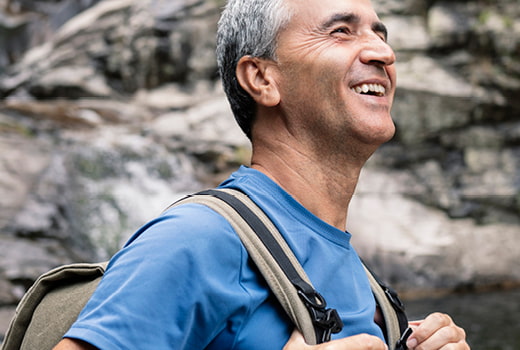 Person near rock wall wearing backpack and blue T-shirt