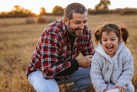 Adult and child laughing in field